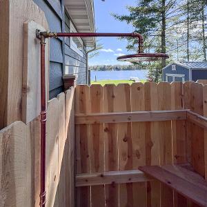 Close-up of the elegant copper-piped outdoor shower, adding a distinctive touch to this lakeside retreat.