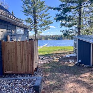 Completed outdoor cedar sauna with copper-piped shower, harmoniously integrated with the existing cabin and overlooking the lake.